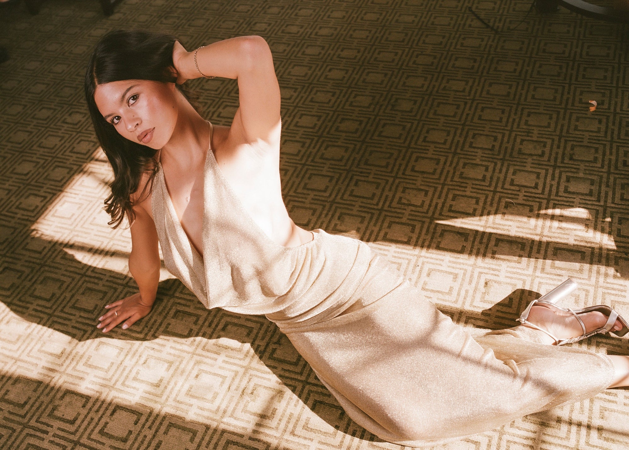 Woman in a flowing dress lying on a patterned carpet
